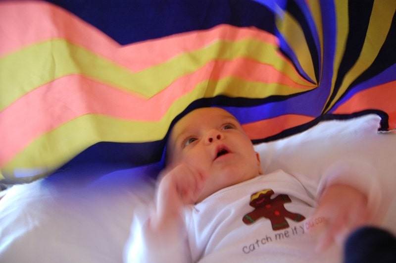 baby playing under silk scarf parachute.