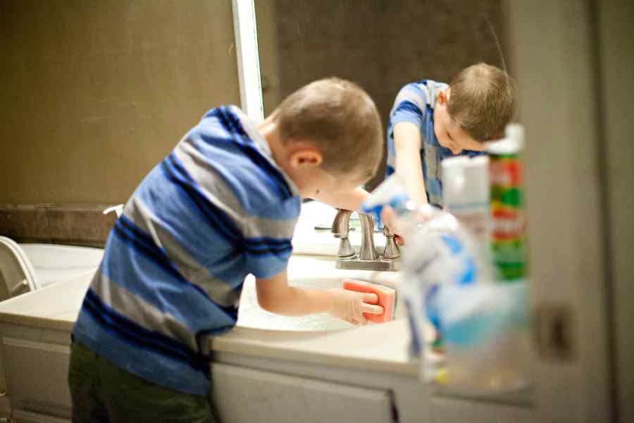 A child cleaning a sink, image from Canva Pro