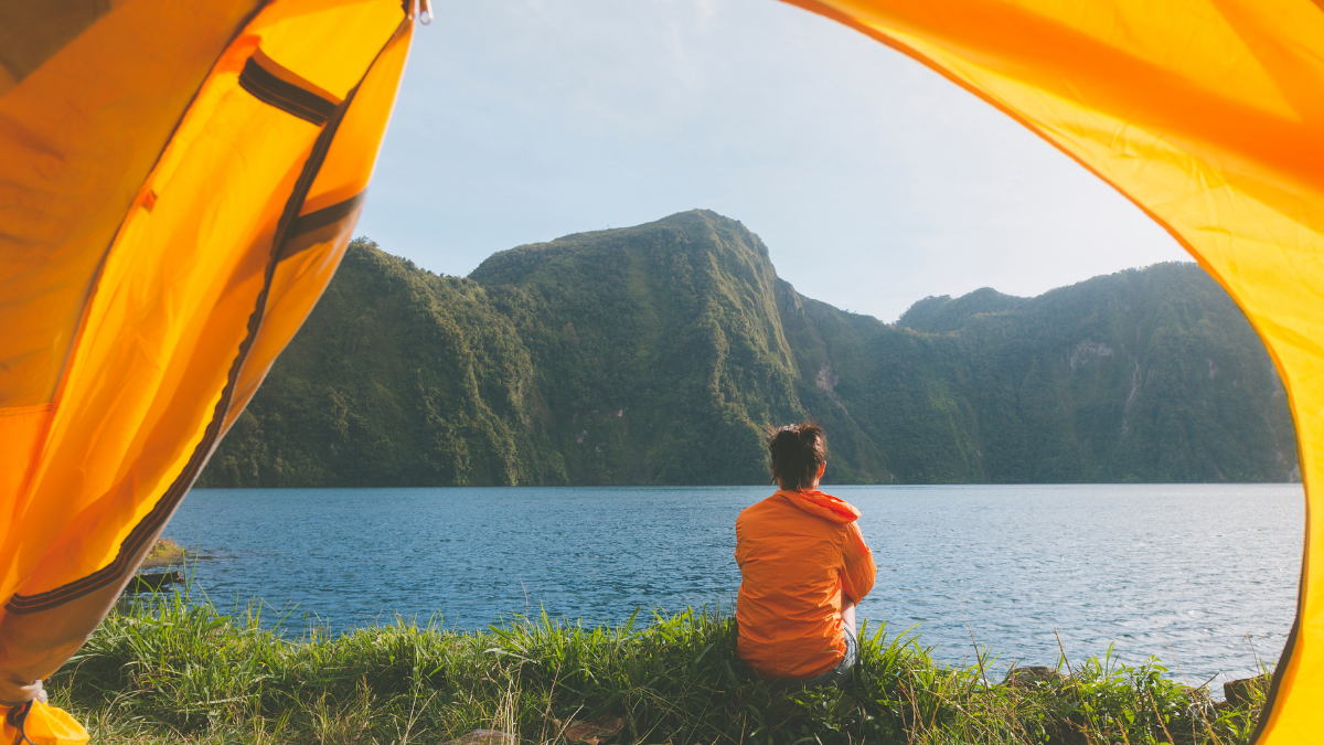 girl sitting by lakeside tent view