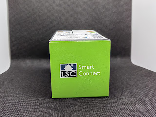 Pudełko z żarówką na szarym tle. Po środku zielony kwadrat a w nim logo LSC Smart Connect