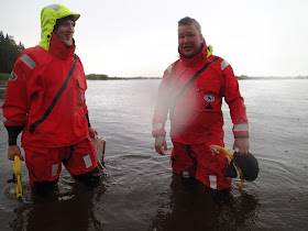 Kaksi pelastautumispukuista miestä rantavedessä