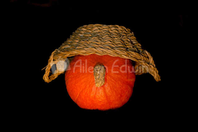 An orange pumpkin wearing a hat on black background