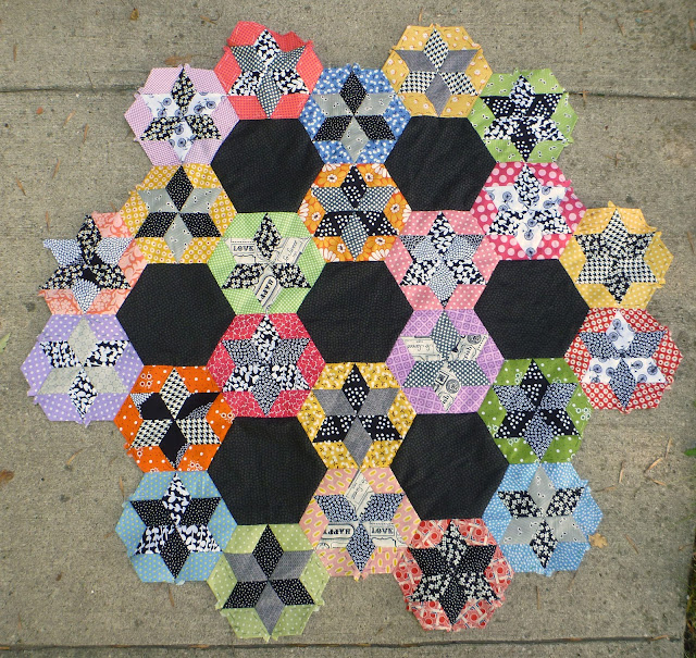 scrap quilt diamond English paper pieced blocks appliquéd onto a black background