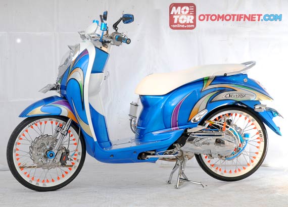 Foto Modifikasi Honda Scoppy tema modif funky simple semua bodi asli dicat ulang dan di airbrush modif tribal yang simple dan memberi warna-warna agak soft seperti ungu oranye cream dan hijau muda di bodi skubebeknya dilengkapi cakram merk TDR di area kaki belakang pun demikian