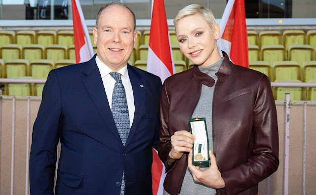 Princess Charlene wore a mock-neck pleated-skirt maxi dress by Akris, and brown nappa leather jacket by Akris Punto