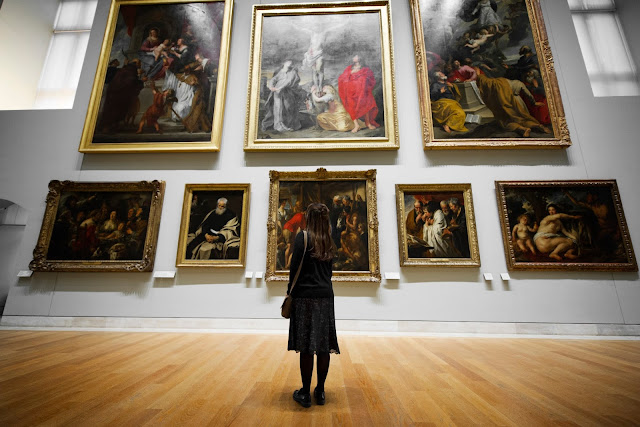 A woman stands watching and appreciating arts