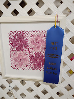 framed tatted square doily made of 4 square pinwheels, with blue ribbon