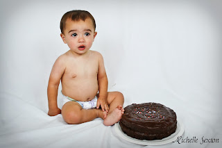 baby sitting next to chocolate cake