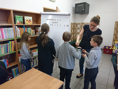 Na zdjęciu bibliotekarz i uczestnicy zajęć feryjnych z odnalezionymi rzeczami