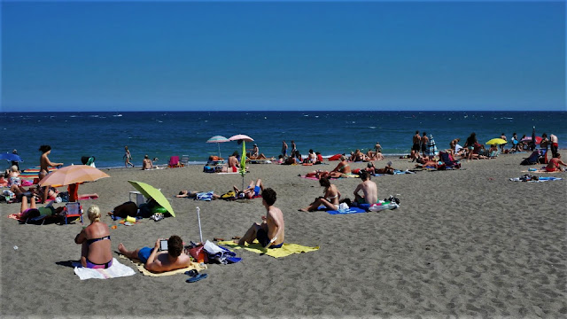 Típica playa de arena llana con mucha gente de vacaciones.