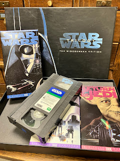 An image of a boxed set of the original Star Wars movie trilogy on VHS tapes, showing the three tapes boxes and the VHS for the first movie