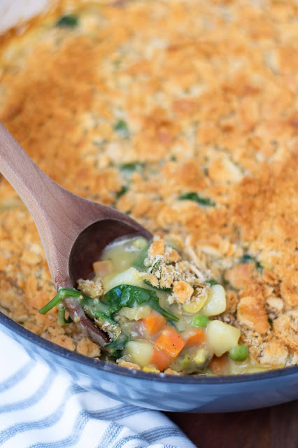 A wooden spoon scooping up and nice serving of the vegetable casserole.