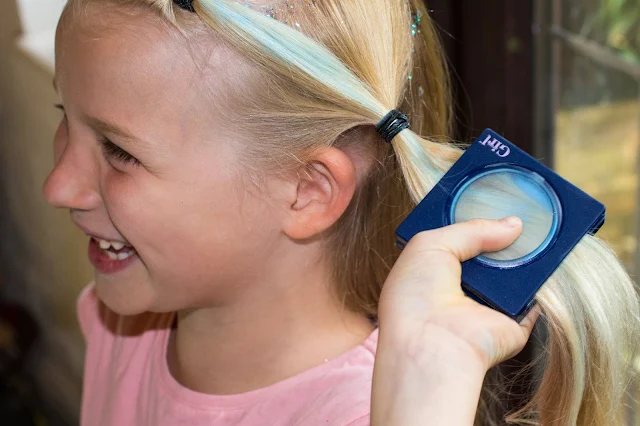 A smiling girl applying blue hair chalk