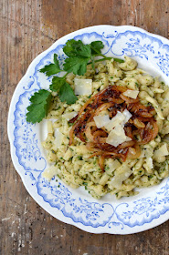 Spätzle mit Bärlauchpesto und karamellisierten Zwiebeln auf einem blau gemusterten Teller.