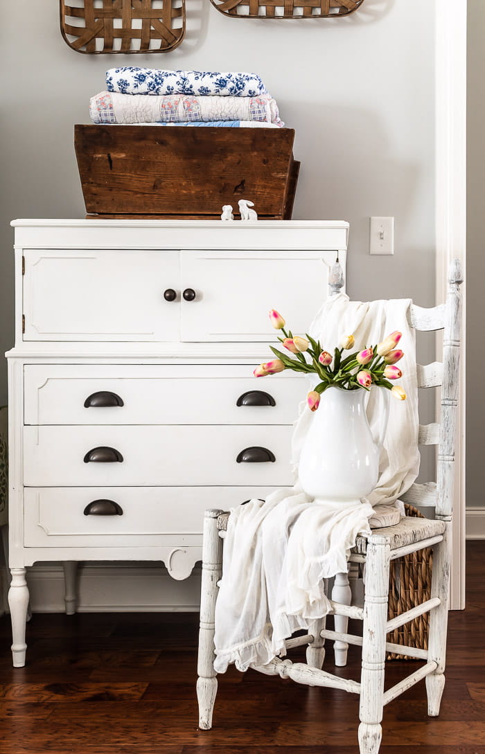 white dresser, tobacco baskets, rustic white chair, pitcher with tulips