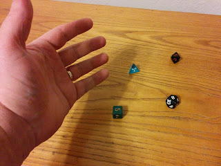 A hand hovers over the table, where several dice have just been rolled. The dice are of different varieties, including d4, d6, d8, and d10.