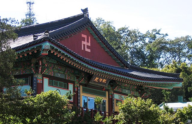 Temple with a large swastika on red background below the roof, South Korea.