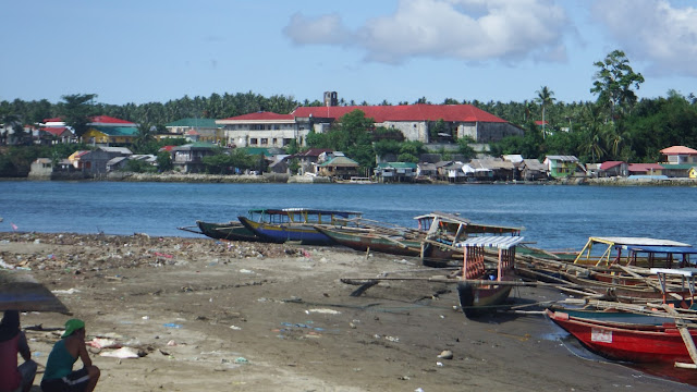 the church and some residential houses across the river as seen from the dirty riverbank of Rawis in Laoang Northern Samar