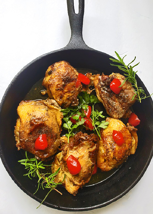 this is cast iron skillet with chicken thighs and tomatoes baked in white wine