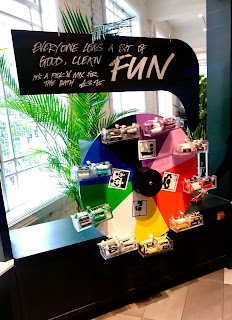 A black circular wheel with small mini black shelve=s filled with cylindrical packets of FUN with a black rectangular sign with FUN in bright white font on a bright background 