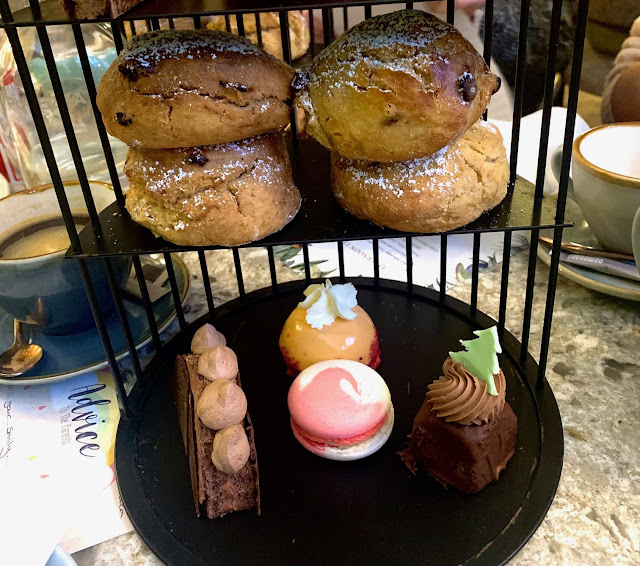 Black birdcage-style cake stand containing four scones and several sweet treats