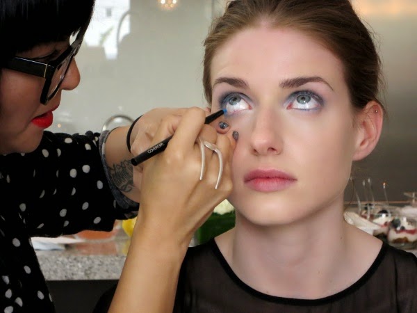 CoverGirl makeup artist lines the model's eyes with blue eyeliner.