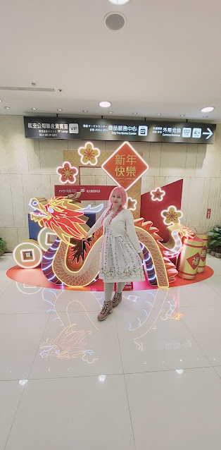 woman with pink hair posin in front of a dragon and smiling into the camera