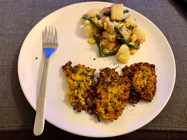 Dinner plate with three cauliflower cutlets, potato salad and a fork