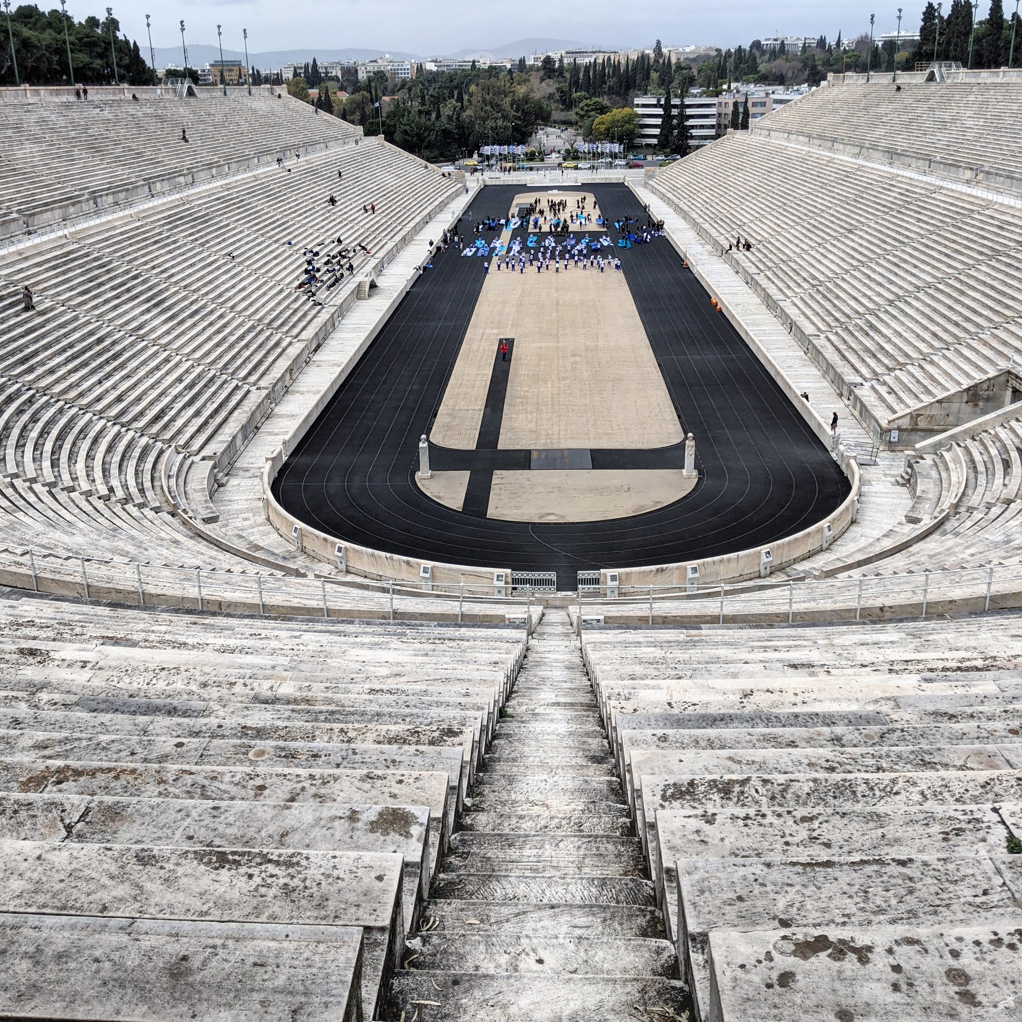 The Panathenaic Stadium in athens with a few people milling around on the steps and track. The monumental stadium is one of the best things to see during a weekend in athens