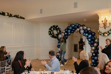 Man walking through balloon arch with arms up