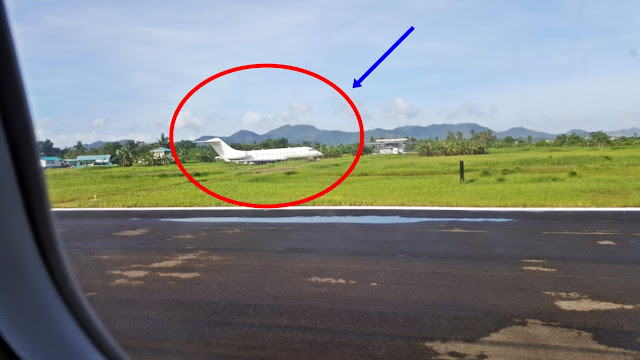 view of an ill-fated plane on the grass beside the runway at Tacloban Airport