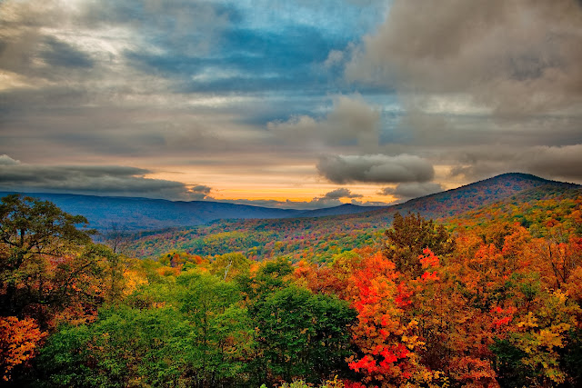 Vibrant fall colors across the trees in upon the mountain tops glow in the evening sun. The clouds above highlight the last glimpses of the autumn sun at the end of the day. Picture Height: 3744 pixels | Picture Width: 5616 pixels | Lens Aperture: f/4 | Image Exposure Time: 1/30 sec | Lens Focal Length mm: 24 mm | Photo Exposure Value: 1.33 EV | Camera Model: Canon EOS 5D Mark II | Photo White Balance: 0 | Color Space: sRGB |