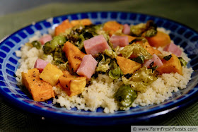 a plate of roasted butternut squash, brussels sprouts, and ham atop a bed of cous cous