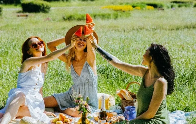 Tre donne che fanno picnic su un prato sotto il sole