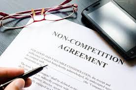 Document Saying Non-Competition Agreement and Hand Holding Pen to Sign