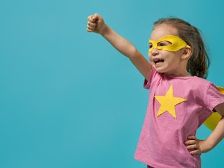 A girl wearing a superhero costume and pretending to fly