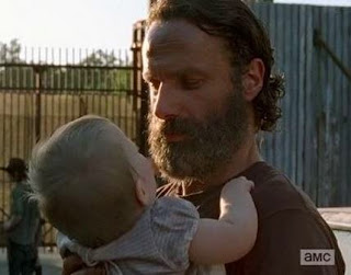 Imagem de Rick com Judith no portão em Alexandria