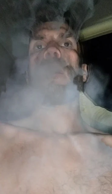 Superior POV shirtless blowing smoke outward staring in the space