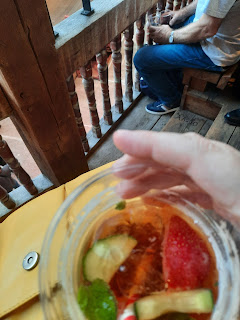 Glass of Pimms in my hand, visibly sitting in the Globe theatre benches