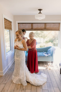 Mother of Bride and Bridesmaid helping bride get into wedding gown