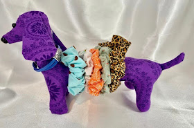 stuffed daschund dog,purple fabric, with scrunchies along its body