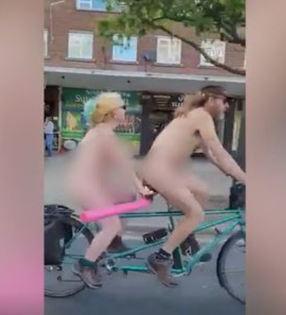 Nude couple seen riding bike along busy street in England while waving at onlookers