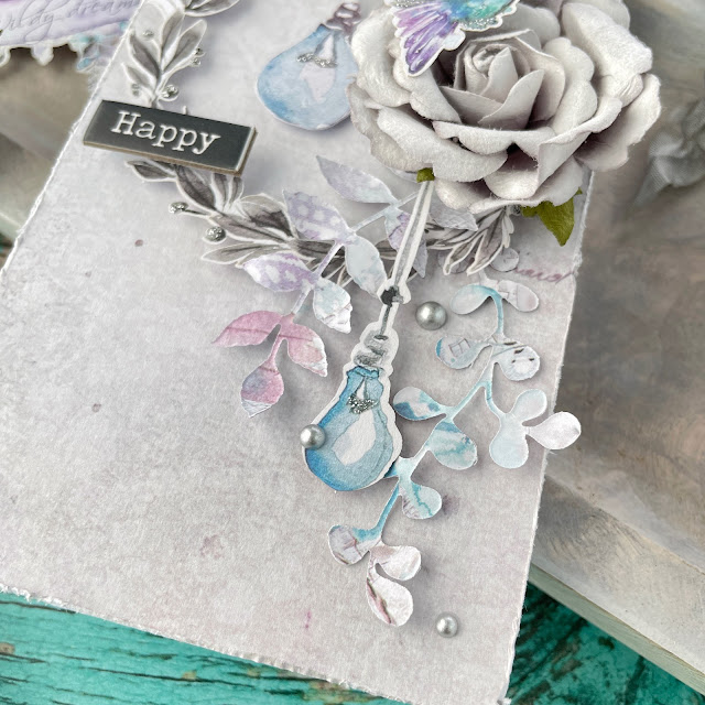 Silvery Grey tags created with: Prima Marketing aquarelle dreams ephemera, paper, flowers, chipboard; Scrapbook.com pops of color glitter silver, delicate leaves die; Pinkfresh matte silver pearls; Tim Holtz distress sprays, crinkle ribbon