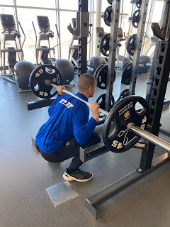 Man performing a weighted back squat in the gym.