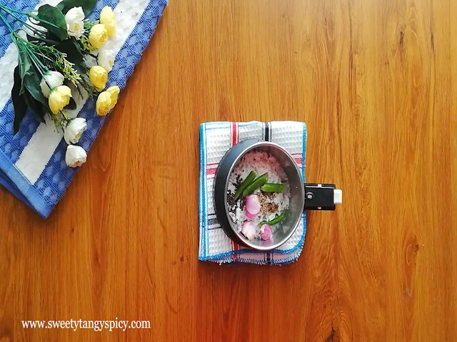 A mixer grinder filled with grated coconut, green chilies, shallots, mustard seeds, cumin seeds, and water, ready to create the aromatic and flavorful coconut paste for Beetroot Pachadi.