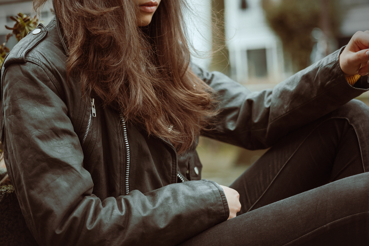 crop portrait of a woman in a stylish leather jacket sitting on a bench
