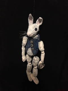 a ceramic marionette of a white rabbit is displayed against a black background