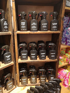 A collection of black spray bottles on rectangular flat shelves of a golden brown rectangular wardrobe on a bright background 