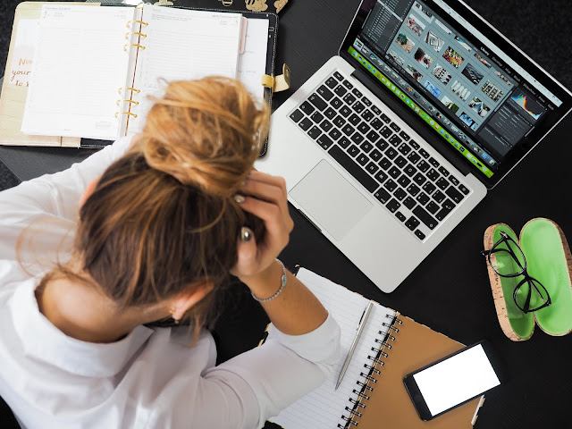 Woman works alone on laptop. Her class organizer sits next to her on the table.