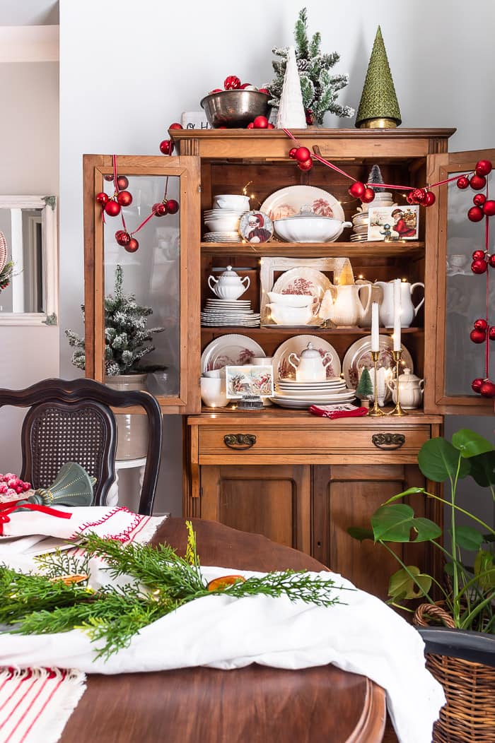 pine hutch with red ornament garland, white ironstone, red and white vintage dishes, bottle brush trees